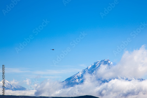 helicoper on backround blue sky in snowing mountain. Volcano Tolbachik. Kamchatka. Russia.