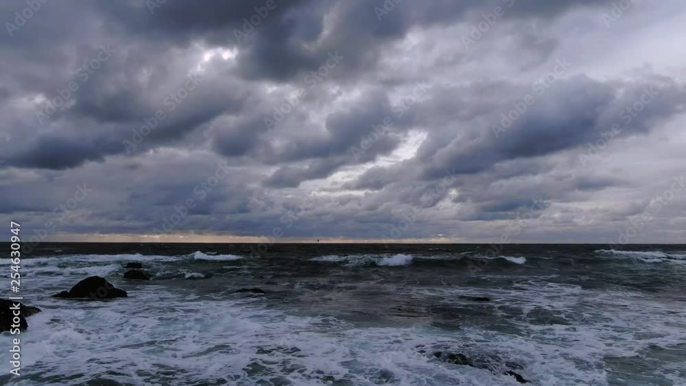 Cloudy sunset deep blue waves crashing on rocky seashore birds and beach Cloudy sunset deep blue waves crashing on rocky seashore birds and beach