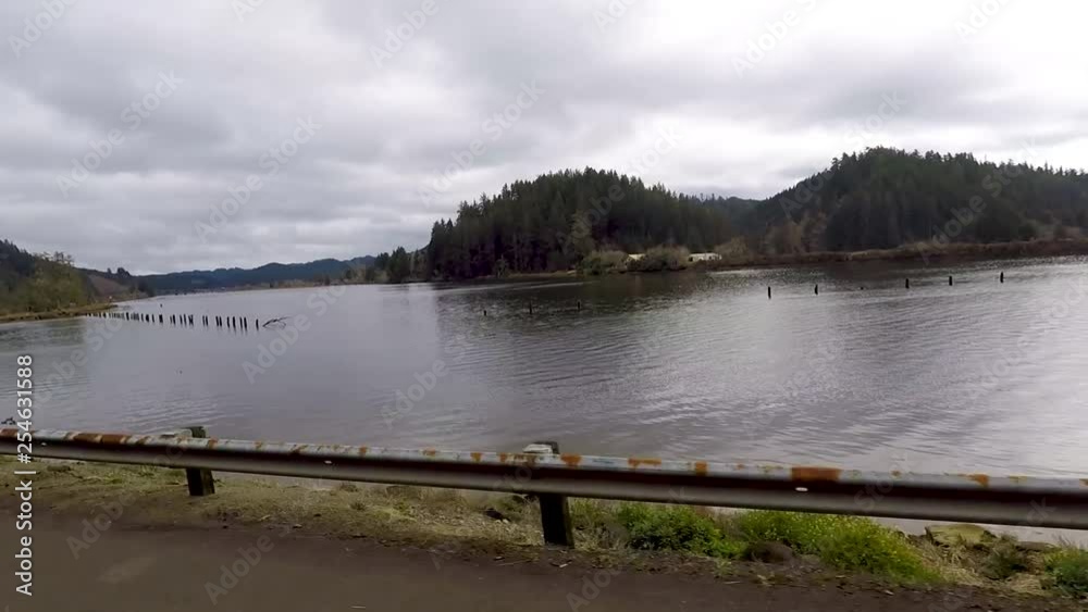 Driving by a river with pilings sticking out of the water that where