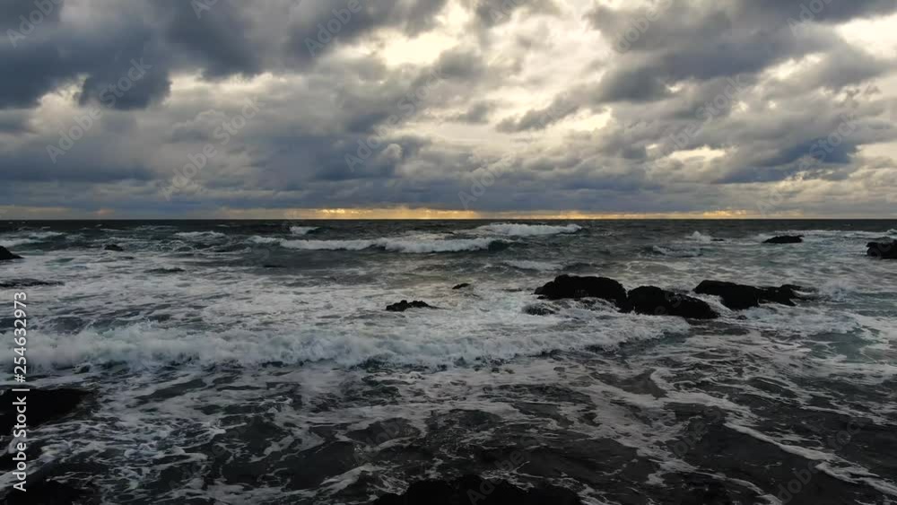 Cloudy sunset deep blue waves crashing on rocky seashore birds and beach Cloudy sunset deep blue waves crashing on rocky seashore birds and beach