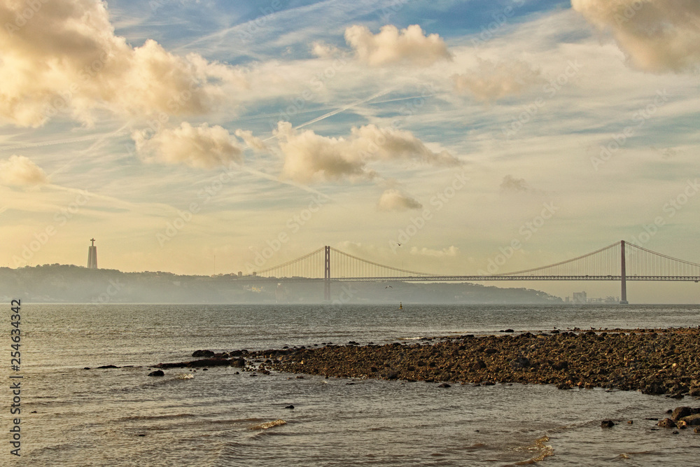 Scenic morning landscape of Tagus river and April 25 bridge with Catholic monument of Christ the King (Almada) at the background. Lisbon, Portugal