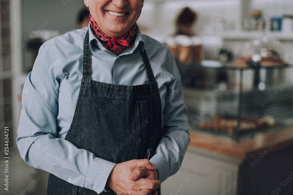 Obraz premium Joyful old man in shirt and apron posing indoors