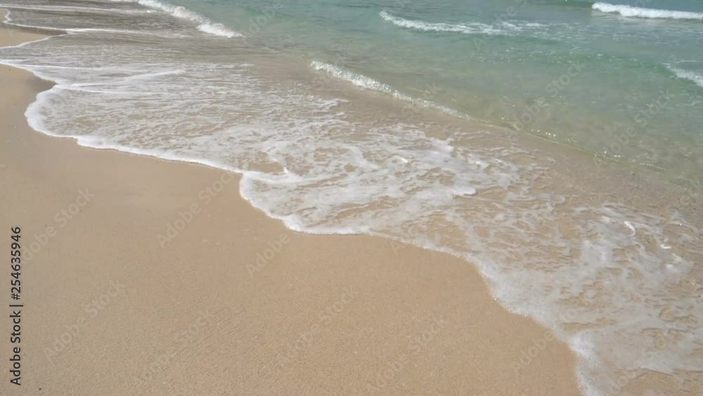 Dull day on a sandy beach with foamy sea waves hitting the shoreline edge, close up shot Dull day on a sandy beach with foamy sea waves hitting the shoreline edge, close up shot