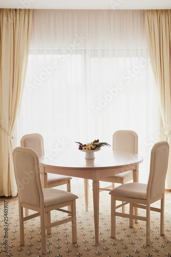 Bright spacious dining room with wooden table, four chairs and big window