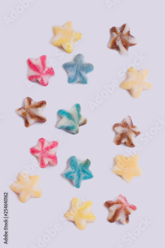 Colored candies scattered on white background. Sugar coated candies in a shape of stars, top view.