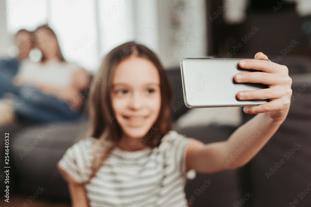 Girl making selfie with parents on background