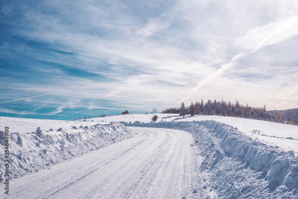 snowy mountain road with blue sky clouds.