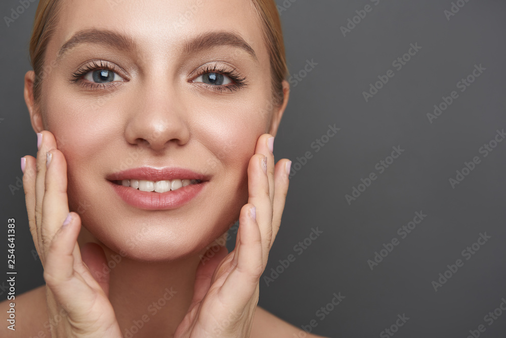 Glad woman touching her skin and smiling cheerfully Glad woman touching her skin and smiling cheerfully