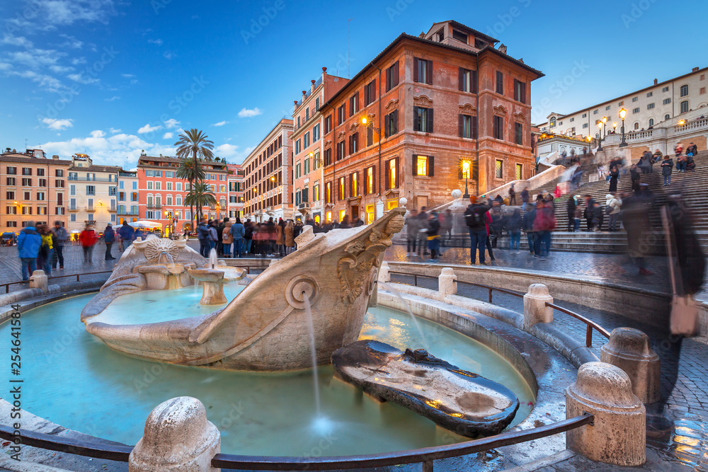 Fountain on the Piazza di Spagna square and the Spanish Steps in Rome at dusk, Italy