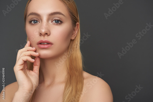 Long haired woman standing with bare shoulders and looking thoughtful
