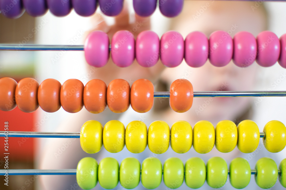 Child in a classroom learning numbers and menthal calculation playing with an abacus. Children education concept. Child in a classroom learning numbers and menthal calculation playing with an abacus. Children education concept.