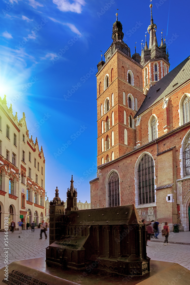 Market square and St. Mary's Basilica in Krakow, Poland in stunning sunset sun light. People tourists walking down the street and relaxing