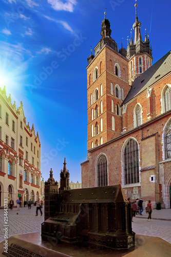 Market square and St. Mary's Basilica in Krakow, Poland in stunning sunset sun light. People tourists walking down the street and relaxing