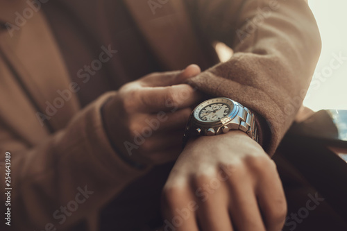 Young man checking time on his elegant wristwatch