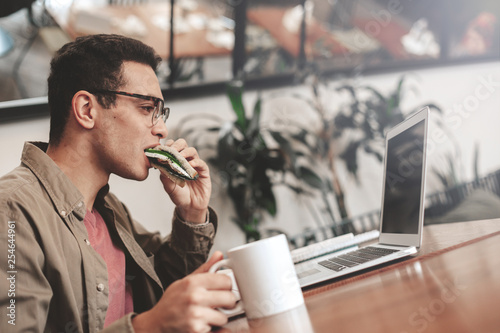 Handsome afro american guy in glasses eating sandwich