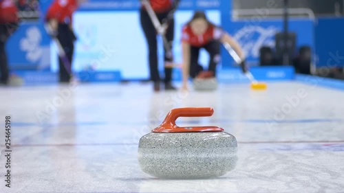 Curling player throw and delivering a stone on a curling rink, sliding over ice
