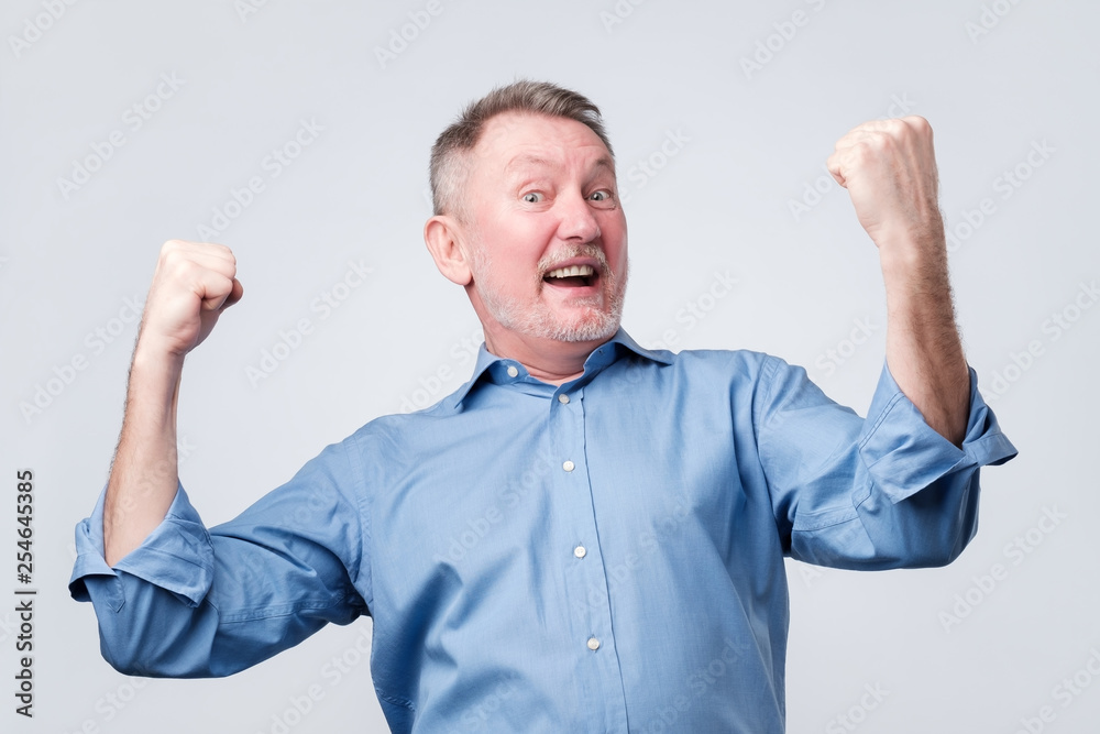 Happy senior strong man, raising clenched fists in hooray gesture, triumphing Happy senior strong man, raising clenched fists in hooray gesture, triumphing