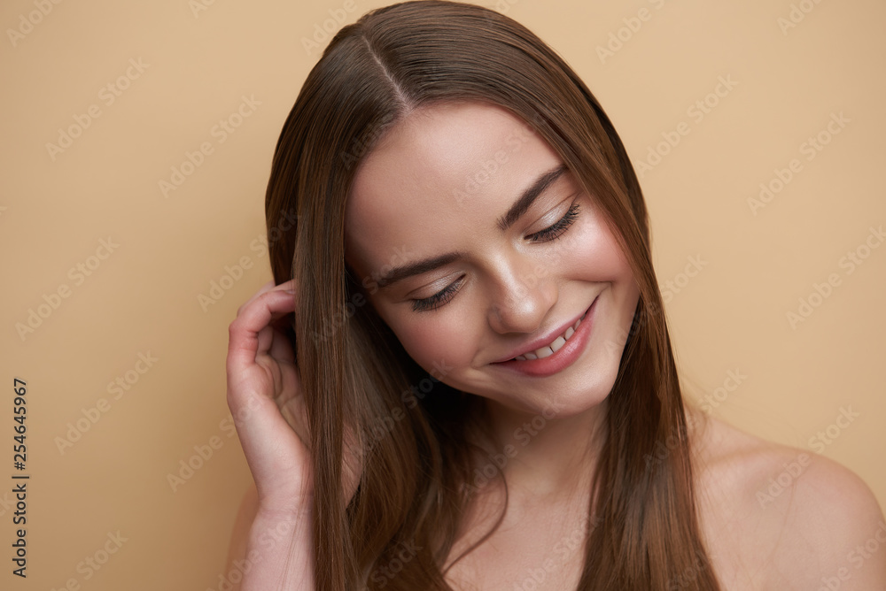 Pleased young lady touching her hair and smiling Pleased young lady touching her hair and smiling