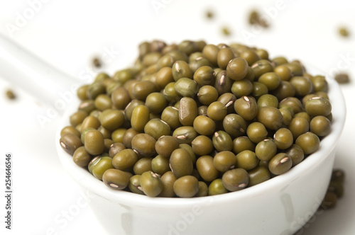 Closeup of mungo beans in a white spoon  on white background