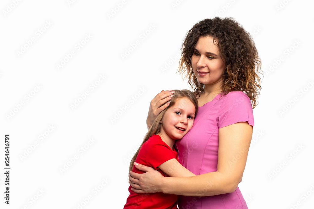 Studio shot of little girl smiling while hugging her mother tightly, isolated with copy space