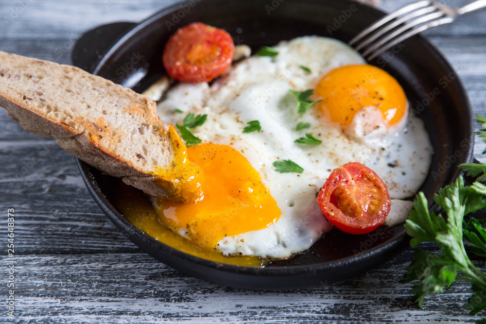 Fried egg. Close up view of the fried egg on a frying pan with cherry tomatoes and parsley Fried egg. Close up view of the fried egg on a frying pan with cherry tomatoes and parsley