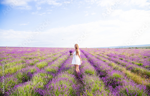 Girl in white dress in field of lavender with bouquet 