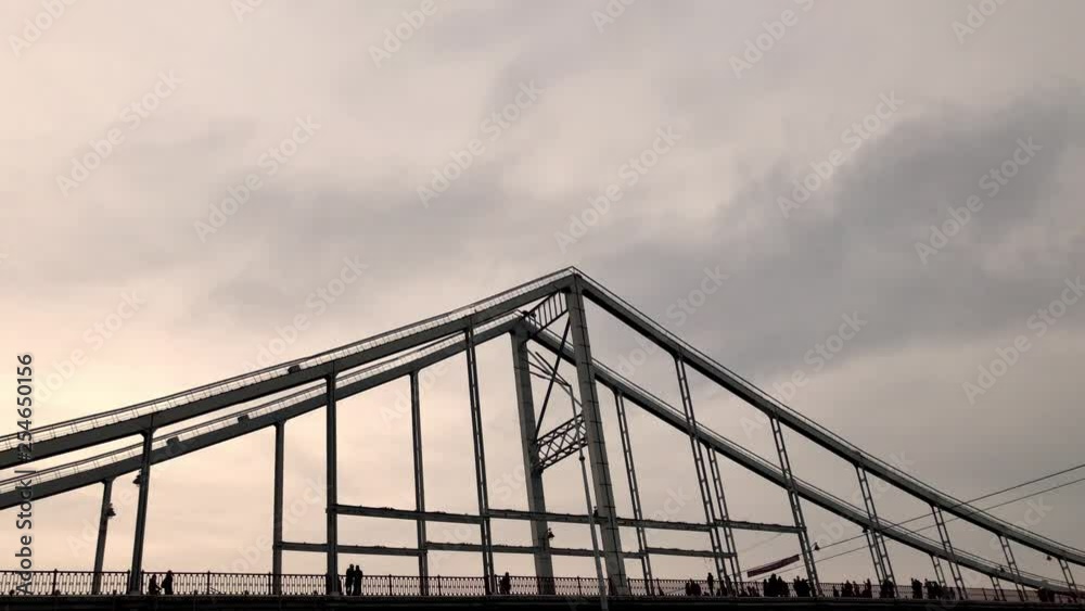 Pedestrian bridge over the river. Silhouette of the bridge on which people walk. Pedestrian bridge over the river. Silhouette of the bridge on which people walk.