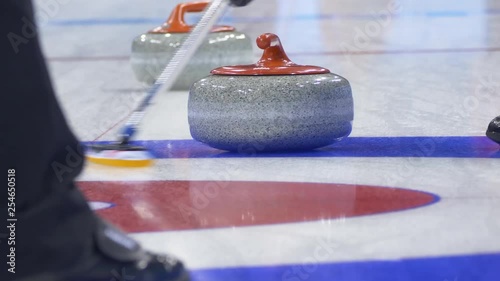 Curling player throw and delivering a stone on a curling rink, sliding over ice