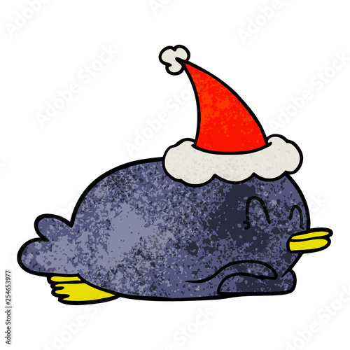 penguin lying on belly wearing santa hat