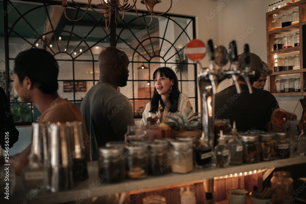 Diverse friends talking over drinks in a bar at night Diverse friends talking over drinks in a bar at night