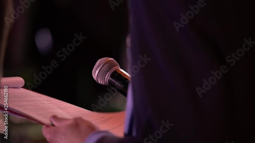 presenter with microphone and folder performs on stage