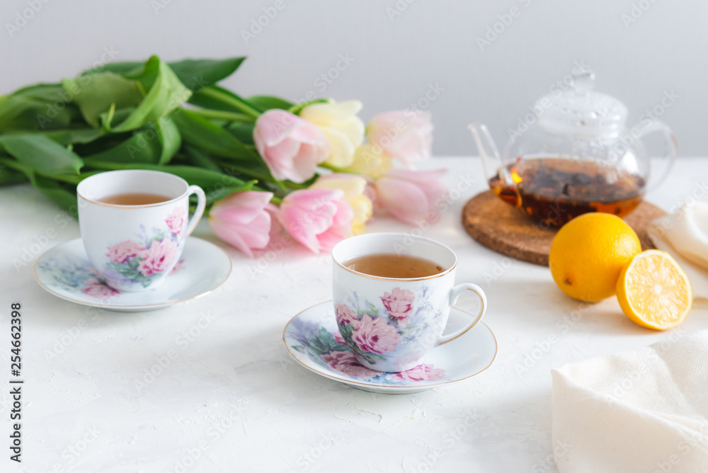Afternoon tea with cake, lemon, teapot and tulips on the background. Tea party. Spring mood, Mother's day concept. Copy space Afternoon tea with cake, lemon, teapot and tulips on the background. Tea party. Spring mood, Mother's day concept. Copy space
