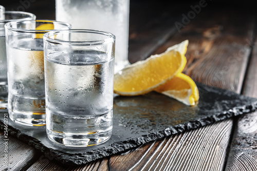Fotografija Vodka in shot glasses on rustic wood background
