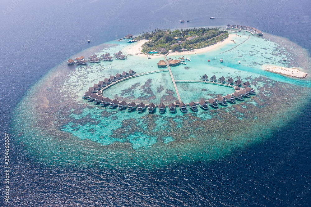 Amazing bird eyes view in Maldives. Perfect aerial view of Maldives luxury island resort, water villas and calm blue sea and green lagoon over coral reef. Luxury vacation and travel