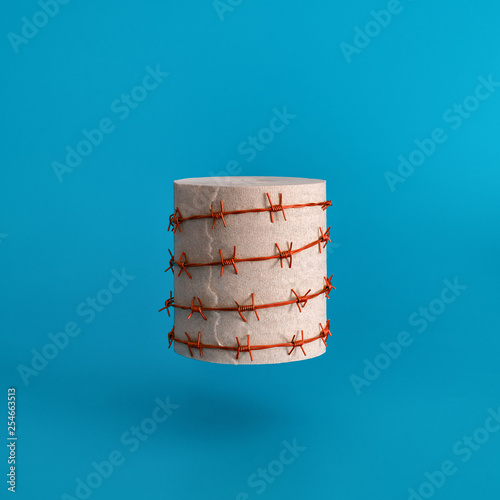 A roll of toilet paper wrapped in red barbed wire on a blue background. Strange funny joke.