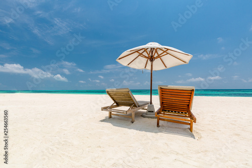 Fototapeta Naklejka Na Ścianę i Meble -  Romantic beach scene, two lounge chairs and umbrella on white sand. Honeymoon or vacation concept, couple and luxury travel background
