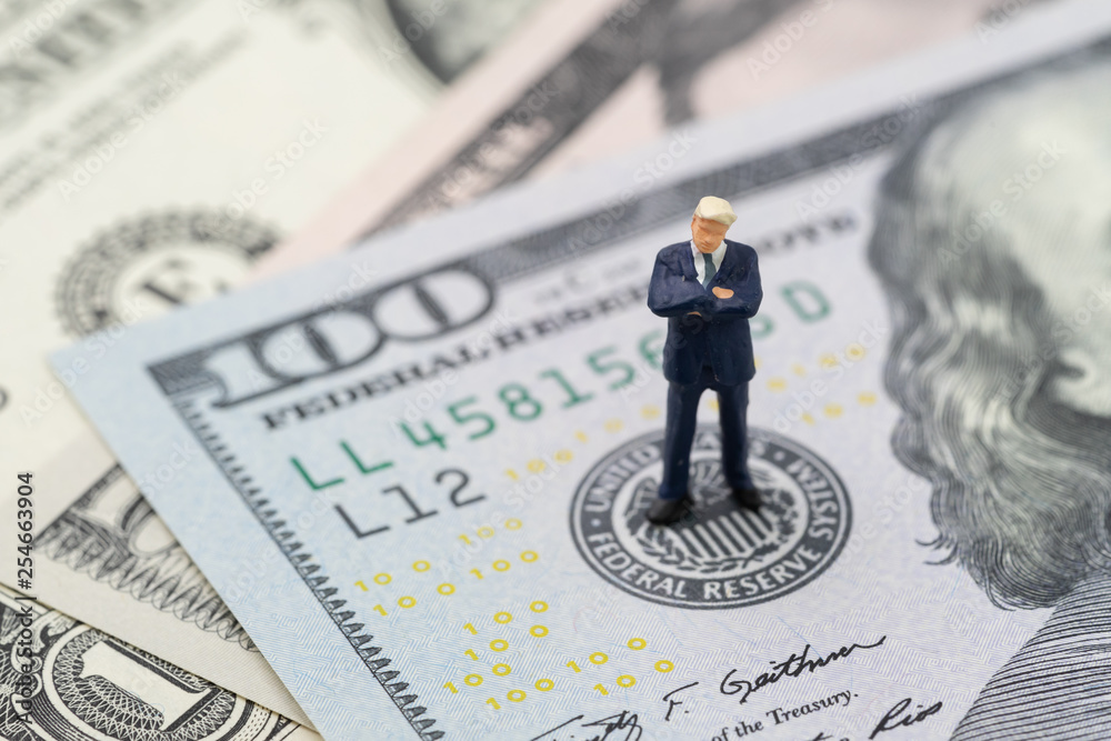 Miniature businessman leader standing and thinking on US Federal Reserve emblem on US dollars banknote as FED consider interest rate hike, economics and inflation control - obrazy, fototapety, plakaty 