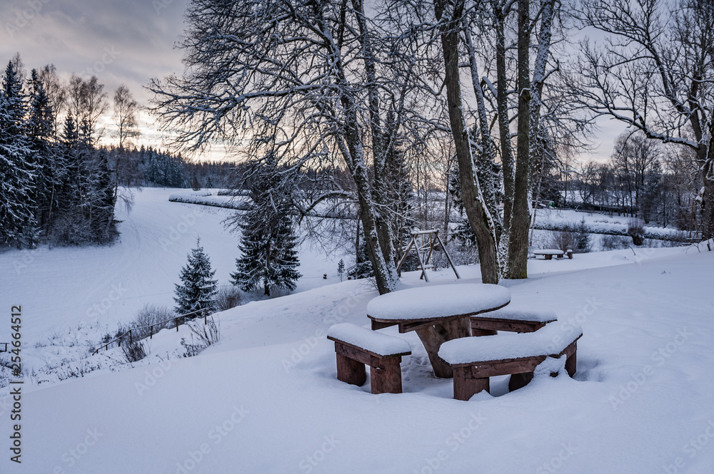 Snow covered resting place with table and benches in outdoor. Kubesele nature trail. Latvia. Baltic.