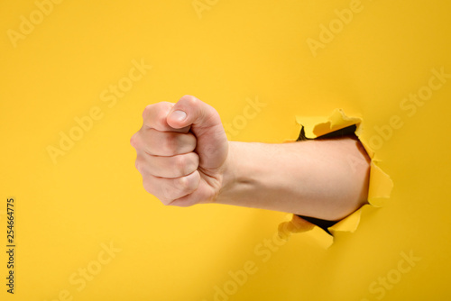 Fist punching through yellow paper photo