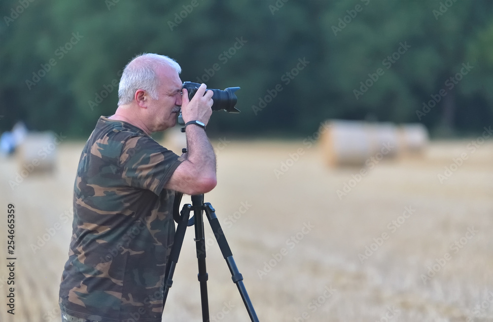 Senior man with camera on a tripod in nature