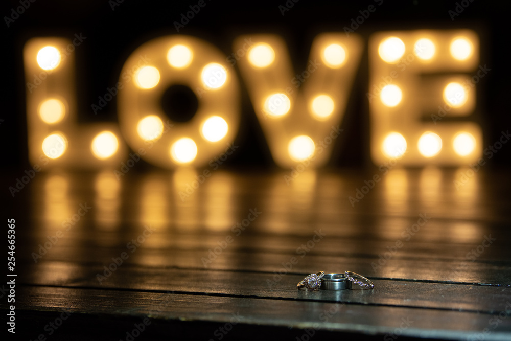 Wedding rings on a table with love in the background Wedding rings on a table with love in the background
