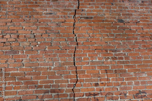 Red brick wall is divided by a vertical crack. Separation concept