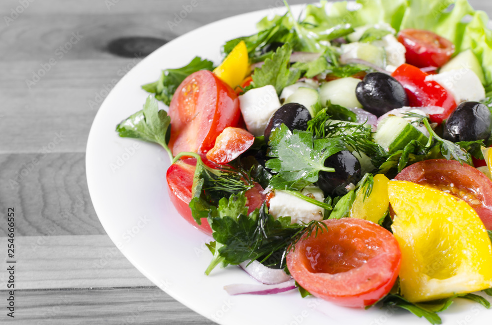 Vegetable salad cucumber capsicum tomato and olives on a white plate genuine black and white background