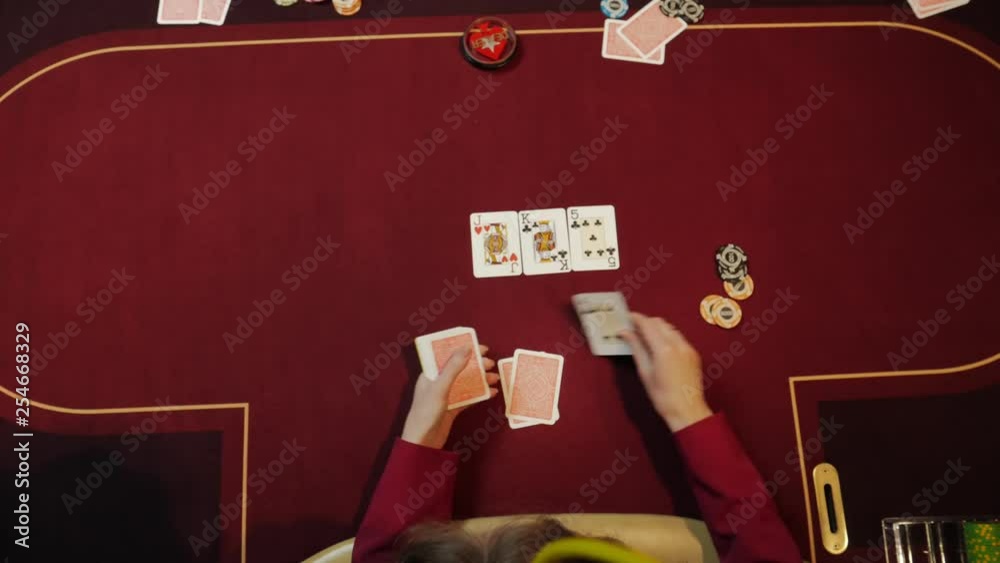 Casino dealer putting cards on red table, poker game, gambling, close-up hands. Top view.