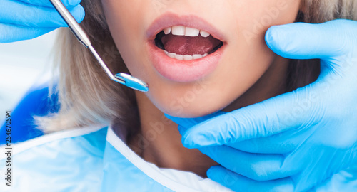 Closeup of dentist examinating blond girl with tool