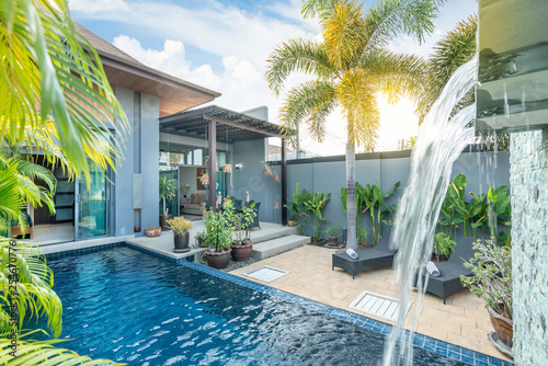 home or house building  Exterior  and interior design showing tropical pool villa with green garden, with sun bed and blue sky 