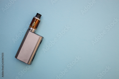 Vape pen metal electronic cigarette with vaping blue background top view