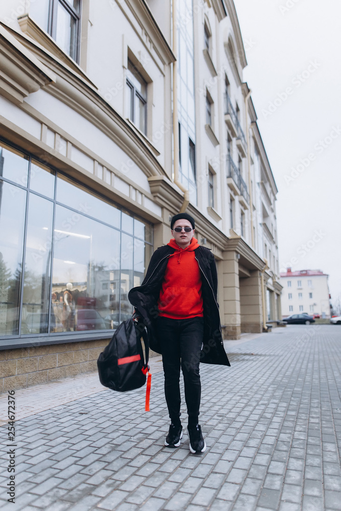Free handsome independent man walking on street of modern luxury district with backpack in fashionable sun glasses. Freedom,traveller, leader man concept