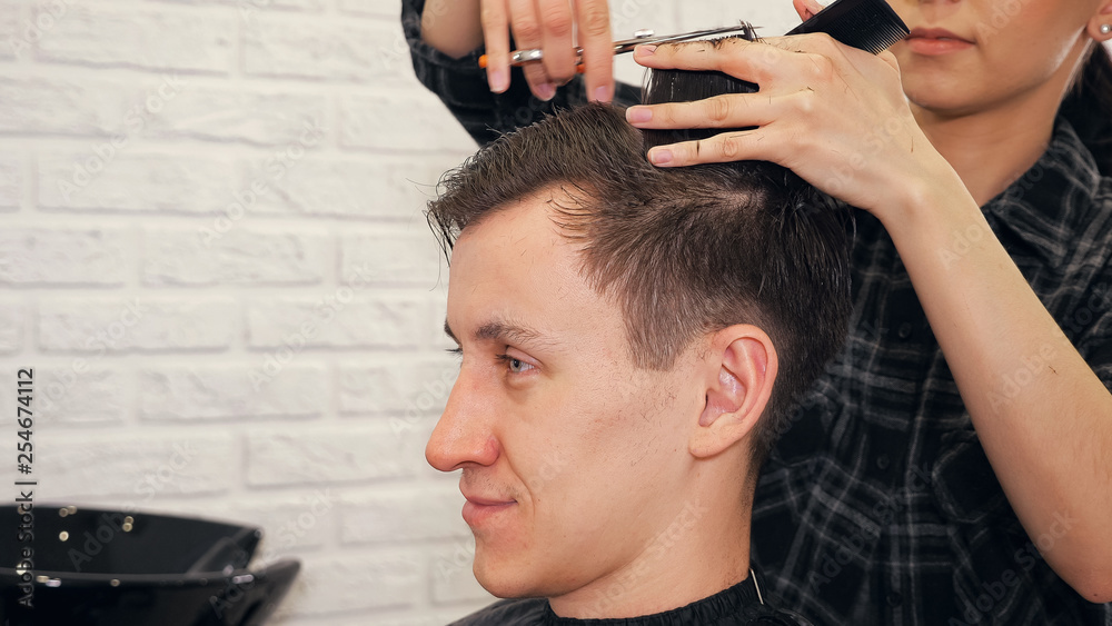 Fototapeta premium Female hairdresser haircut doing male hair style.