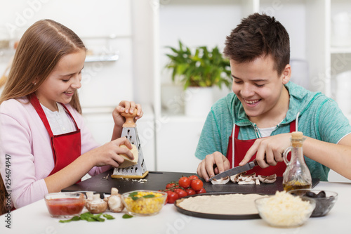 Happy teenagers having fun in the kitchen preparing a pizza